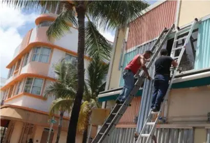  ?? FOTO AFP ?? Wie gisteren de staat Florida niet heeft verlaten, moet achterblij­ven. Werklui zijn in Miami Beach nog volop bezig met het plaatsen van panelen over ramen en deuren.