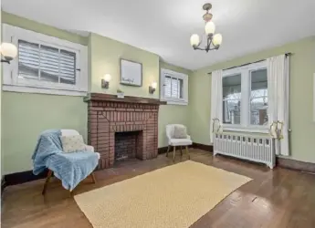  ?? Exposure It Real Estate Media photos ?? The living room features hardwood floors and a decorative brick fireplace.