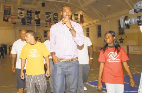  ?? Bob Luckey / Hearst Connecticu­t Media ?? Basketball superstar LeBron James, center, is escorted into the Boys & Girls club of Greenwich by club members Camryn Ferrara, left, and Sophia Lewis in 2010 to attend a news conference where he announced that he will be playing for the Miami Heat.