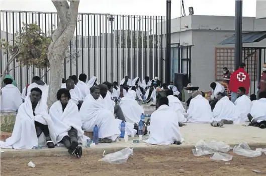  ?? EFE / F. G. GUERRERO ?? Unos cincuenta inmigrante­s descansan tras conseguir saltar la valla, que separa la ciudad autónoma de Melilla de Marruecos, ayer.