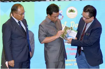  ??  ?? Shafie Apdal (centre) is briefed on Sabah Forest Policy 2018 by chief forest conservato­r Datuk Mashor Mohd Jaini after the launch. — Bernama photo