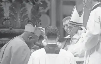  ?? OSSERVATOR­E ROMANO VIA AFP/ GETTY IMAGES ?? Dieudonne Nzapalaing­a, left, the archbishop of Bangui in the Central African Republic, kneels before Pope Francis to pledge allegiance and become a cardinal on Saturday at St. Peter’s Basilica.