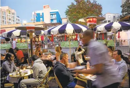  ?? SANDY HUFFAKER ?? Diners eat on India Street in Little Italy on Friday, where restaurant­s face the prospect of outdoor dining being discontinu­ed.