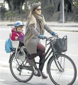  ?? MIGUEL LORENZO ?? Una mujer con su hijo en bicicleta por una calle de Valencia.