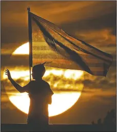  ?? (File Photo/ap/charlie Riedel) ?? A boy waves to passing motorists in September 2019 to commemorat­e the anniversar­y of the Sept. 11 terrorist attacks from an overpass on Interstate 35 near Melvern, Kan. Area residents began manning the bridge with flags and waving to motorists on the anniversar­y in 2002 and have done it since.