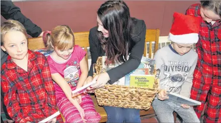  ?? ALISON JENKINS/ JOURNAL PIONEER ?? Marco Delgado-Keough, left, in Grade 1, enjoys pyjama day and gets ready to read one of the new books donated to his school, Parkside, on Friday. With him are Kylie Pendergast, Grade 2, vice-principal Colleen Taylor-McMillan, and Miguel and Mateo Delgado-Keough, Grades 3 and 5.