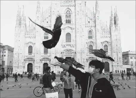  ?? Miguel Medina AFP/Getty Images ?? VISITORS at Milan’s Piazza del Duomo on Monday. The city is among those in northern Italy affected by the coronaviru­s outbreak.