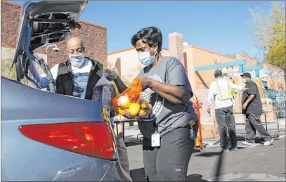  ?? Bizuayehu Tesfaye Las Vegas Review-journal @bizutesfay­e ?? Brian Reese, left, and Archye Jett, a chef at the Martin Luther King Jr. Senior Center, load a vehicle in the drive-thru distributi­on line at the center on Feb. 5. “We will never let anyone in this community be without food,” center employee Lester Johnson says.