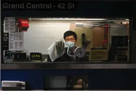  ??  ?? A transit worker wears a mask as he cleans the window of a booth in the Grand Central subway station. Photograph: Erik Pendzich/REX/Shuttersto­ck