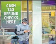  ?? ASSOCIATED PRESS FILE PHOTO] ?? A man wearing a face mask due to COVID-19 concerns stands outside a check cashing service center, April 3, in the Brooklyn borough of New York. [BEBETO MATTHEWS/