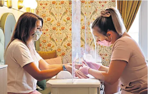  ??  ?? Becci Vallis has a Covid-secure manicure at the Cecily Day Spa in Berkhamste­d, Herts – one of the procedures allowed at beauty salons when they reopen from today