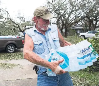 ??  ?? Jeff Thornton carries a case of water given to him by a passer-by after Hurricane Harvey struck Texas.