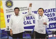  ??  ?? President Rodrigo Duterte raises the hand of his top aide Christophe­r Lawrence “Bong” Go, after he filed his certificat­e of candidacy.