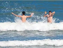  ?? JiM MicHAuD / BoSTon HeRALD ?? JUMP IN, THE WATER’S FINE: Teens jump through the waves at Lynn Beach on Sunday.