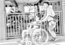  ??  ?? An Election Commission employee pushing the wheelchair of Julita Kamijan, 80, to her polling station at Sekolah Menengah Kebangsaan Limbanak polling station in Penampang. - Bernama photo