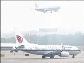  ??  ?? An Air China airplane approaches for landing as other airplanes are parked on the tarmac in Beijing. The representa­tive body of China’s four major carriers says it will not comply with the carbon tax.