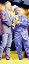  ??  ?? Capleton receives his award from Dr Carey Wallace (left) of the Tourism Enhancemen­t Fund.