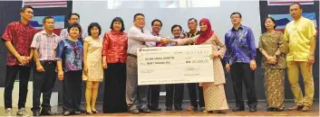  ??  ?? Alani Othman (fourth right) presenting a mock cheque of RM20,000 to Shim Nyuk Min while Koh Kah Leong (seventh from right) and school staff look on.