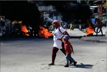  ?? Foto: Reuters/Ralph Tedy Erol ?? En kvinde og et barn må gå forbi braendende barrikader i Port-au-Princes gader.