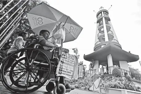  ?? MACKY LIM ?? LOCATION, LOCATION. A person with disability selling candles parks his wheelchair near the candle lighting area inside San Pedro Cathedral yesterday morning to sell more.