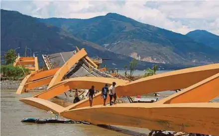  ?? REUTERS PIC ?? People walking on a broken bridge hit by an earthquake and tsunami in Palu, Sulawesi, yesterday.