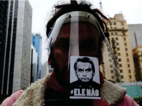  ?? (Reuters) ?? A man in Sao Paolo wears a face shield with a sticker of President Bolsonaro that says ‘Not him’