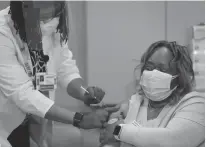  ?? Tribune News Service/chicago Tribune ?? Nurse clinician Vicki Johnson gives ER nurse Tracy Everett her second COVID-19 vaccine at Stroger Hospital in Chicago on Jan. 7. Across the country, vaccine uptake among long-term care workers remains low.