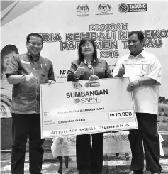  ??  ?? Ghaffar (left) presenting a contributi­on to Mary while Tawau Education Department officer, Darman Shah looks on.