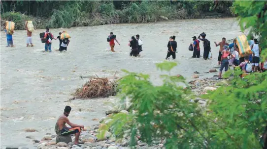  ?? / AFP ?? Migrantes venezolano­s cruzaron el río Táchira, en la frontera con Colombia, para dejar su país; usan esta vía por cuenta del cierre del paso fronterizo.