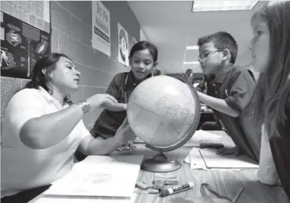  ?? Photos by Andy Cross, The Denver Post ?? From left, parent tutor Evelia Soriano works with students Erine Avorque, 7; Edwin Benton, 7; and Lily Vigil-Stein, 7; during a vital Denver Public Schools Foundation program called Each One Teach One at Marie L. Greenwood Academy.