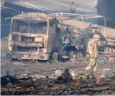  ?? EFREM LUKATSKY/AP ?? A Ukrainian soldier walks past a burning military truck on Saturday in Kyiv.