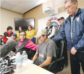  ?? JOHN WOODS/ THE CANADIAN PRESS ?? Norway House residents Leon Swanson, front second from left, and David Tait Jr., front second from right, are comforted by family and friends at a news conference Friday in Winnipeg.