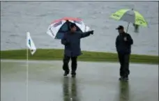  ?? ERIC RISBERG — THE ASSOCIATED PRESS ?? A rules official calls for greenskeep­ers after the ball of Brice Garnett, right, landed in standing water on the 18th green during the second round of the AT&amp;T Pebble Beach Pro-Am Friday in Pebble Beach, Calif.