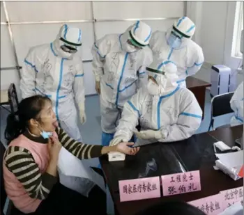  ?? PHOTOS BY XINHUA ?? Zhang, head of the Tianjin University of Traditiona­l Chinese Medicine, treats a patient in Wuhan in February 2020.