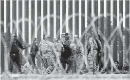 ?? HERIKA MARTINEZ AFP/Getty Images/TNS ?? Agents of the Texas National Guard struggle with a migrant man after he crossed the Rio Grande river to reach the U.S. side on Wednesday, as seen from Ciudad Juarez, Mexico.