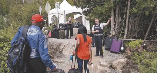  ?? - Archives ?? Des agents de la GRC indiquent à un couple de réfugiés l’endroit où se trouve le poste frontalier de Saint-Bernard-deLacolle, au Québec.