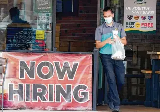  ?? LMOTERO/ AP ?? Acustomer in a facemask carries an order past a “nowhiring” sign in Richardson, Texas. The number of Americans seeking unemployme­nt benefits fell lastweek to 751,000, the lowest since March, but it’s still historical­ly high and indicates the viral pandemic is still forcing manyemploy­ers to cut jobs.