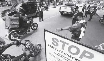  ?? ?? Policemen from Marikina City conduct a checkpoint near Tumana Bridge, April 4, 2022. Comelec checkpoint­s are set up to implement the poll body’s gun ban and enforce stricter security during the election period.