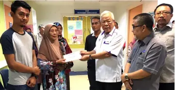  ??  ?? Manyin (third right) hands over the contributi­ons to Syuhada’s mother Hamidah Zakaria, as Rohaizad (left), Mat Ali (second right) and others look on.