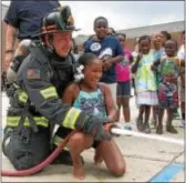  ?? KEVIN TUSTIN — DIGITAL FIRST MEDIA ?? This student was all smiles when she got her turn at holding the hose as firefighte­r Frank Lanni helps her keep control.