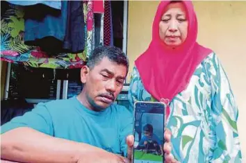  ??  ?? SAFARUDDIN dan isterinya, Zaharah menunjukka­n gambar Muhammad Amin yang ditemui mati lemas di parit dekat Apartmen Dahlia, Taman Bunga Raya, Bukit Beruntung.