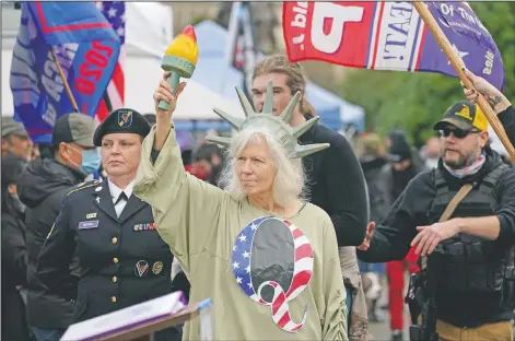  ?? (File Photo/AP/Ted S. Warren) ?? A person dressed as Lady Liberty wears a shirt with the letter Q, referring to QAnon, as protesters take part in a protest Jan. 6 at the Capitol in Olympia, Wash., against the counting of electoral votes in Washington, affirming President Joe Biden’s victory.