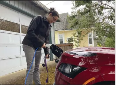  ?? (AP/Gillian Flaccus) ?? Rebecca DeWhitt charges her electric vehicle late last month in the driveway of the Portland, Ore., home she rents.