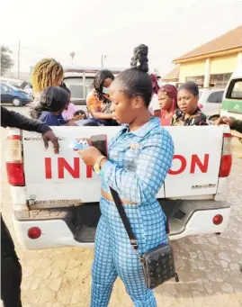  ?? ?? The suspected trafficker standing holding tickets while the victims are seated in a van after their journey was interrupte­d by NAPTIP officials