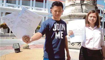  ?? PIC BY SHAHNAZ FAZLIE SHAHRIZAL ?? Penang Gerakan Youth acting chief Jason Loo (left) showing the writs of summons received from Penang Chief Minister Lim Guan Eng at the Penang High Court yesterday. With him is Penang Gerakan Women committee member Peggy Khoo.