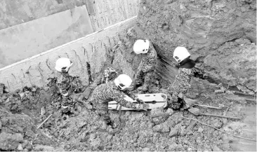  ??  ?? Fire and Rescue personnel removing the Bangladesh­i worker’s body from the rubble. - Bernama photo