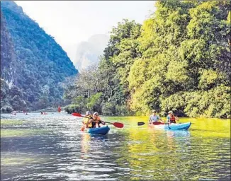  ??  ?? KAYAKERS on the Nam Song River glide by towering karsts, the pointy mountains that dot Laos.