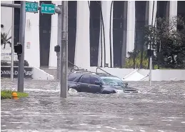  ?? MIKE STOCKER/SOUTH FLORIDA SUN-SENTINEL ?? Floodwater­s from Hurricane Irma failed to deter this driver Sunday on Brickell Avenue in Miami.