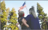  ??  ?? Left: Jena Terrill, holding her daughter Emma, 1, both of Lodi, look at the raised American flag during the Celebrate America event at the West Park at Hutchins Street Square in Lodi on Wednesday.