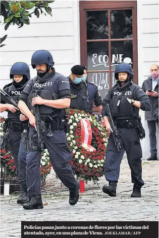  ?? JOE KLAMAR / AFP ?? Policías pasan junto a coronas de flores por las víctimas del atentado, ayer, en una plaza de Viena.